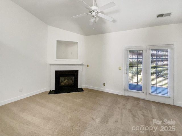 unfurnished living room with visible vents, carpet floors, a ceiling fan, and a fireplace with flush hearth