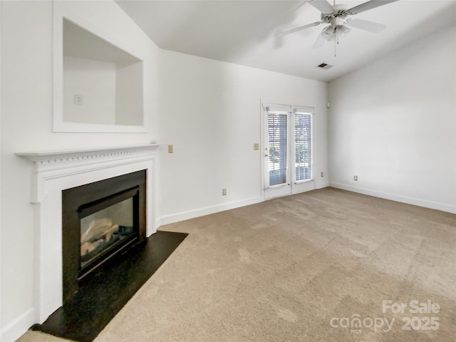 unfurnished living room with visible vents, a fireplace with flush hearth, carpet, baseboards, and ceiling fan