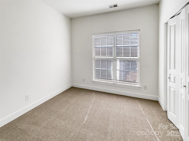 carpeted spare room featuring baseboards and visible vents