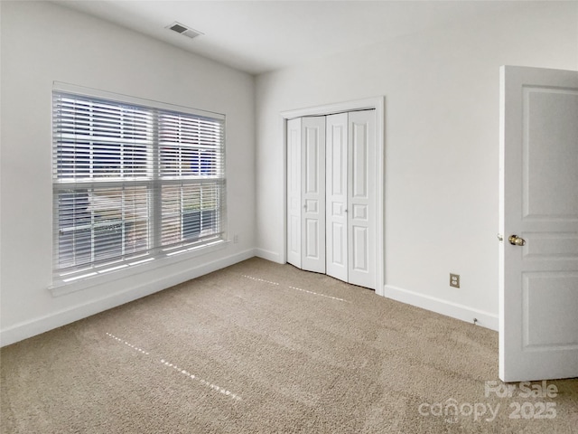 unfurnished bedroom with visible vents, carpet floors, baseboards, and a closet