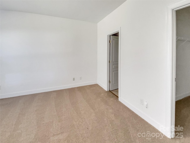 unfurnished bedroom featuring a walk in closet, baseboards, and carpet