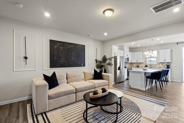 living area featuring recessed lighting, visible vents, baseboards, and light wood-style flooring