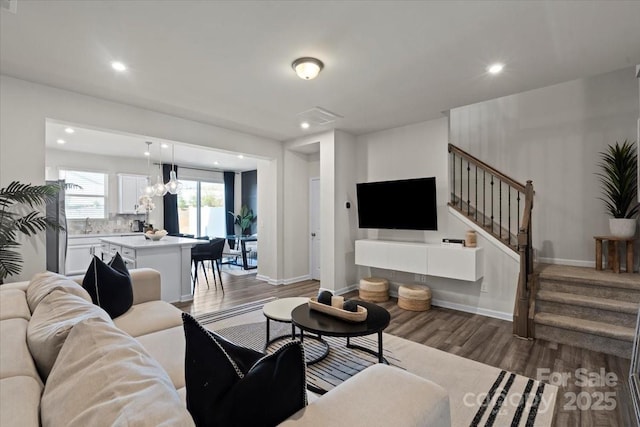 living area featuring stairway, baseboards, visible vents, and wood finished floors