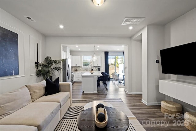 living room featuring recessed lighting, visible vents, baseboards, and dark wood finished floors