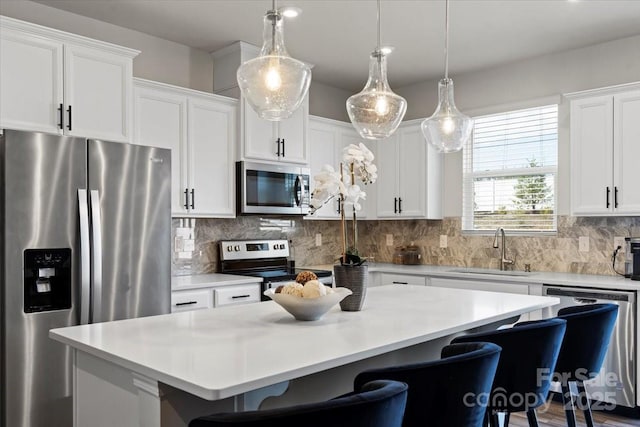 kitchen featuring a kitchen island, a breakfast bar area, decorative backsplash, stainless steel appliances, and a sink