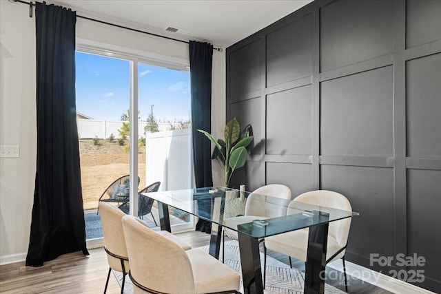 dining room featuring a decorative wall, light wood-style floors, and visible vents