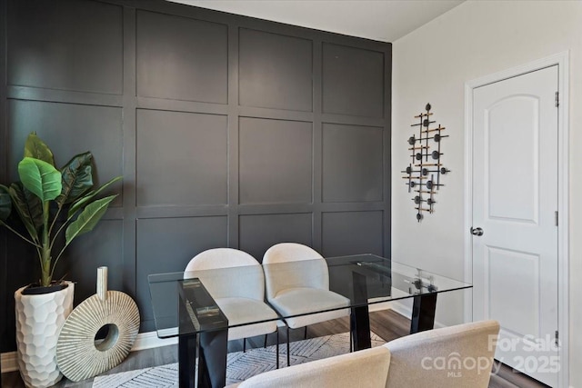 dining room with a decorative wall and dark wood-style flooring