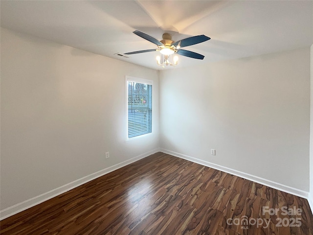 spare room with a ceiling fan, visible vents, dark wood-style floors, and baseboards