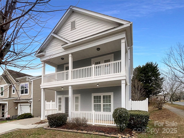 view of front facade with covered porch, a balcony, and fence