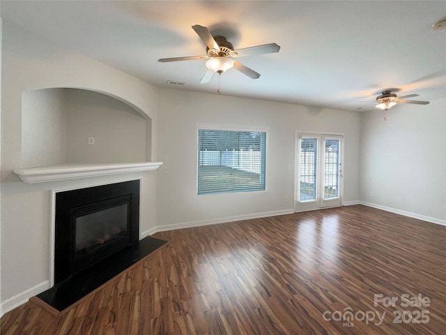 unfurnished living room with a glass covered fireplace, wood finished floors, and baseboards