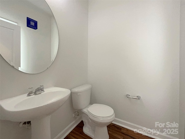 bathroom featuring toilet, baseboards, and wood finished floors