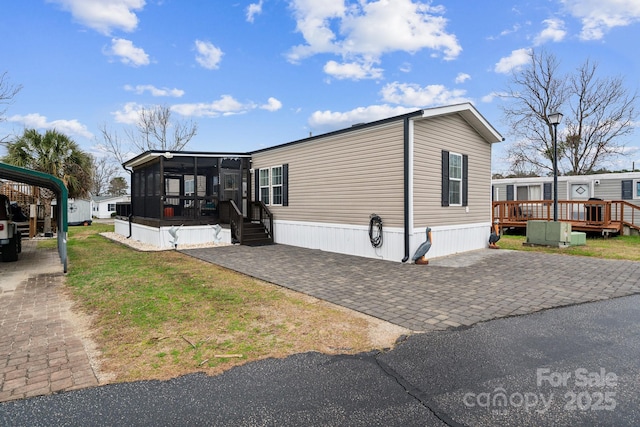 view of front of home with a front lawn, driveway, a sunroom, and a wooden deck