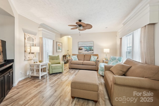 living room featuring ceiling fan, a textured ceiling, ornamental molding, and light wood finished floors