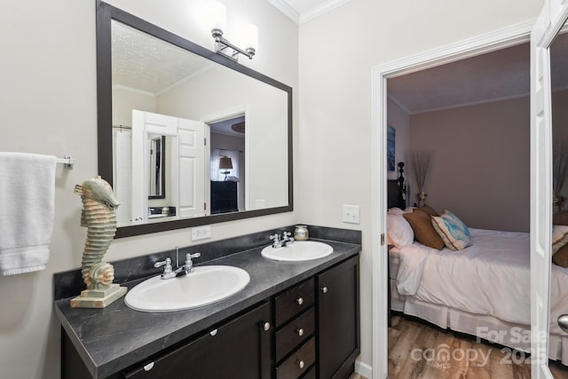 ensuite bathroom with a sink, wood finished floors, ensuite bathroom, and crown molding