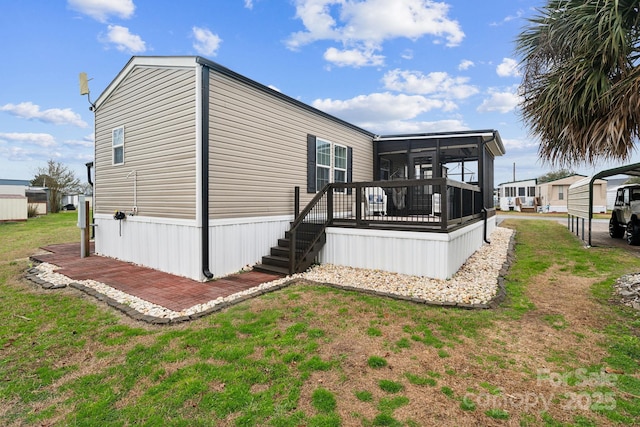 back of property featuring a deck, a yard, and a sunroom