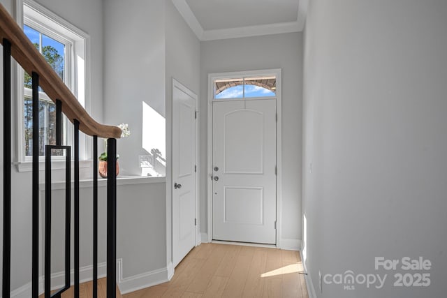 foyer with stairs, light wood-type flooring, baseboards, and ornamental molding