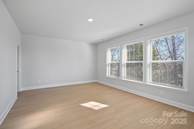 unfurnished room with visible vents, light wood-style flooring, and baseboards