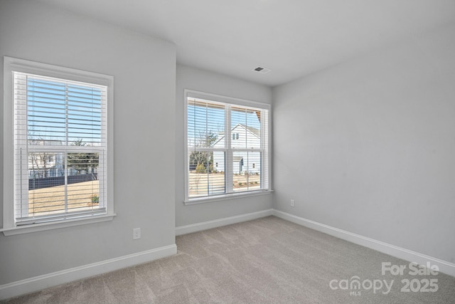 unfurnished room with visible vents, baseboards, and light colored carpet