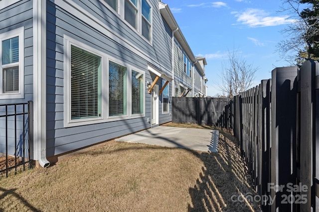 view of side of property featuring a yard, a patio, and a fenced backyard