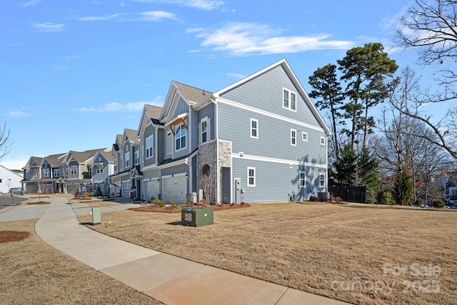 view of side of property with stone siding, a residential view, board and batten siding, and an attached garage