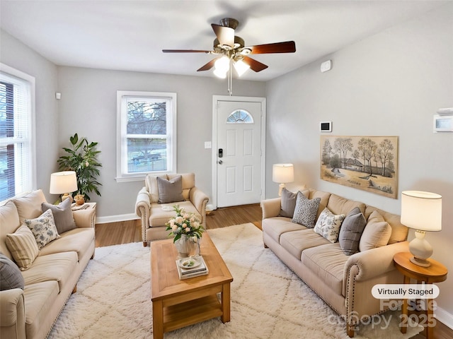 living room featuring ceiling fan, baseboards, and wood finished floors