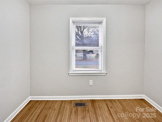 spare room featuring visible vents, baseboards, and wood finished floors