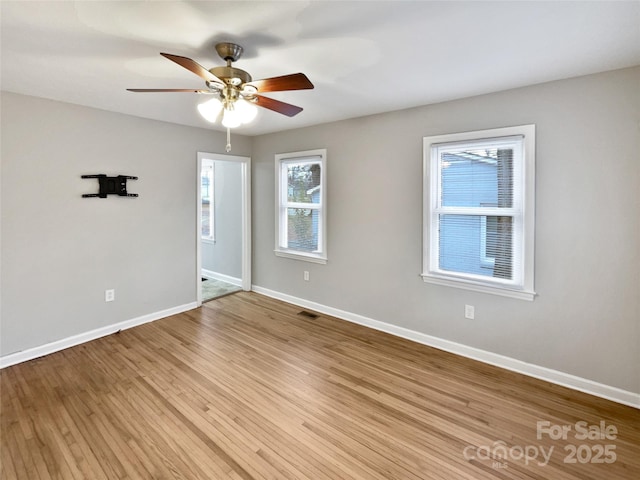 spare room featuring a ceiling fan, light wood-style flooring, baseboards, and visible vents