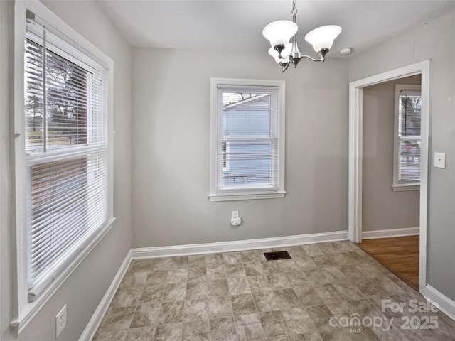 unfurnished dining area featuring a chandelier, visible vents, and baseboards