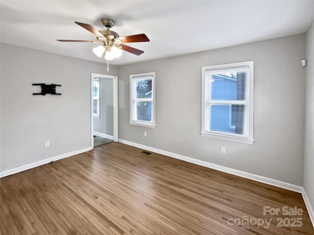 unfurnished room featuring a ceiling fan, wood finished floors, baseboards, and visible vents