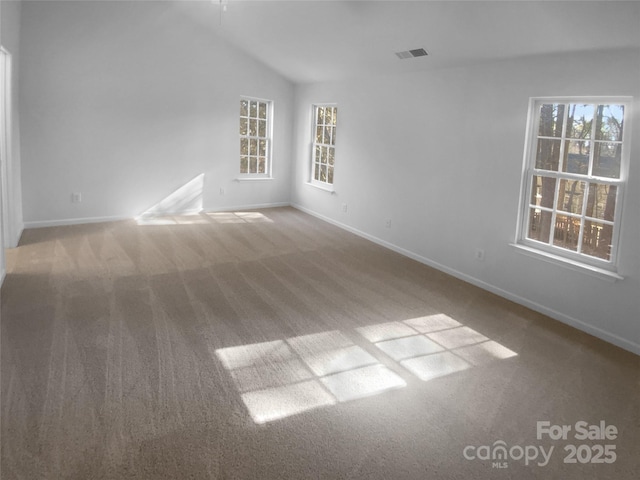 carpeted empty room featuring visible vents, baseboards, and vaulted ceiling