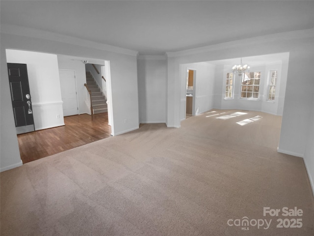 unfurnished living room featuring carpet floors, crown molding, baseboards, a chandelier, and stairs