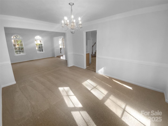 spare room with a chandelier, ornamental molding, baseboards, and carpet floors