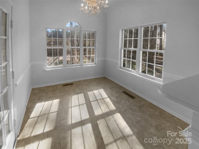 unfurnished dining area featuring a notable chandelier, visible vents, and baseboards