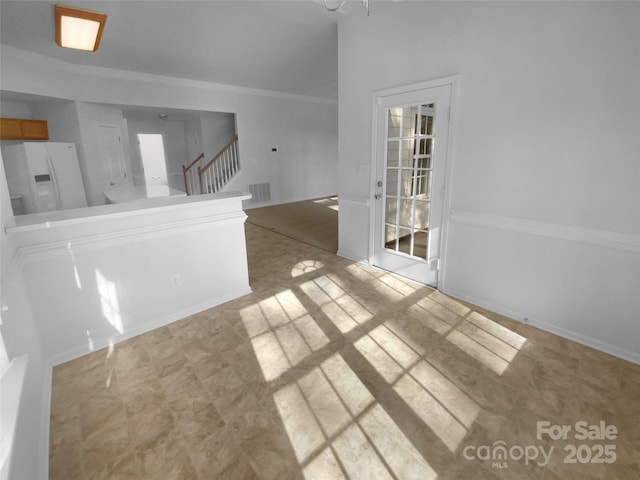 spare room featuring stairs, visible vents, and ornamental molding