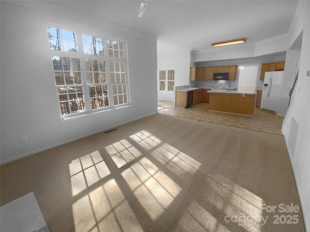 unfurnished living room featuring visible vents, light carpet, baseboards, and ornamental molding