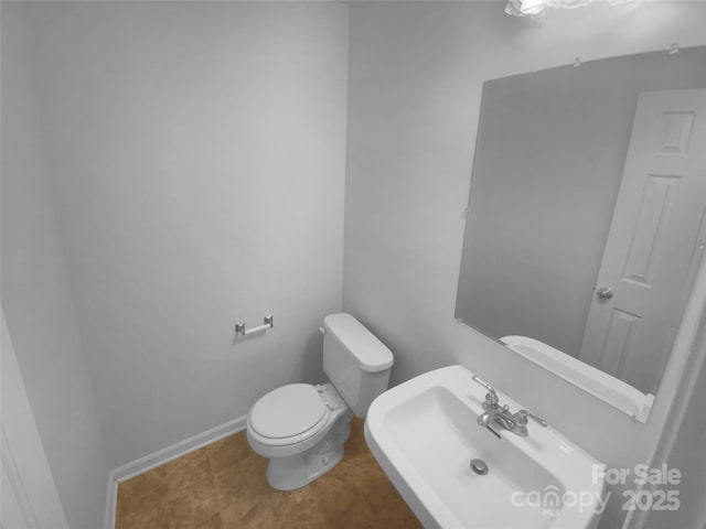 bathroom featuring toilet, baseboards, and a sink