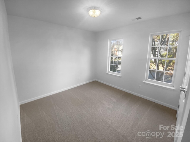 carpeted spare room with a wealth of natural light, visible vents, and baseboards