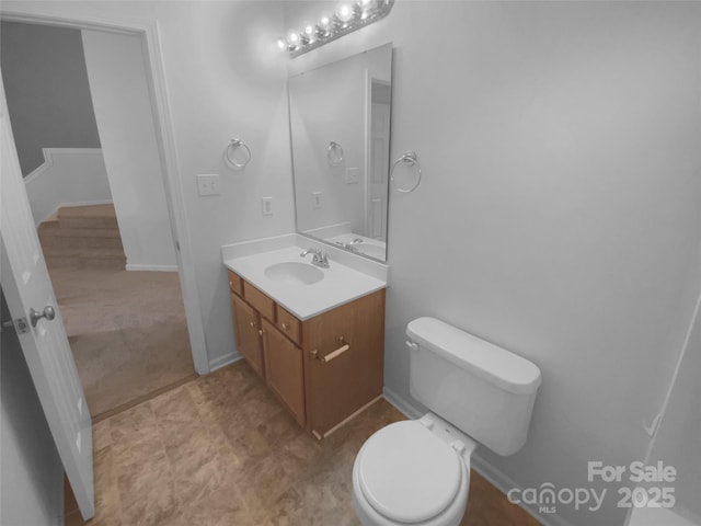 bathroom with toilet, vanity, and baseboards