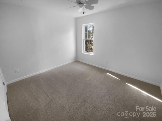 carpeted spare room with a ceiling fan and baseboards