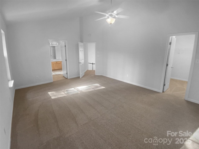 unfurnished bedroom with carpet, baseboards, high vaulted ceiling, a spacious closet, and ensuite bathroom