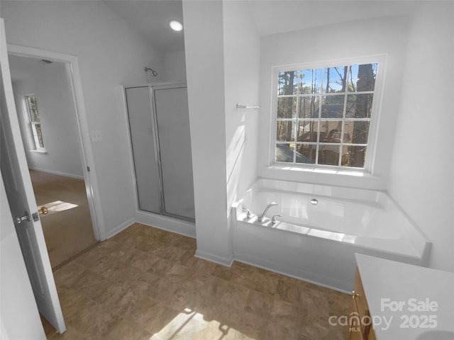 bathroom featuring a shower stall, a bath, and baseboards