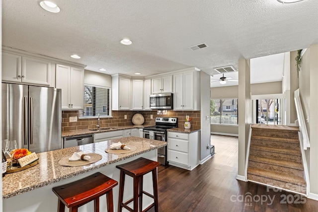 kitchen with a sink, stainless steel appliances, visible vents, and a ceiling fan