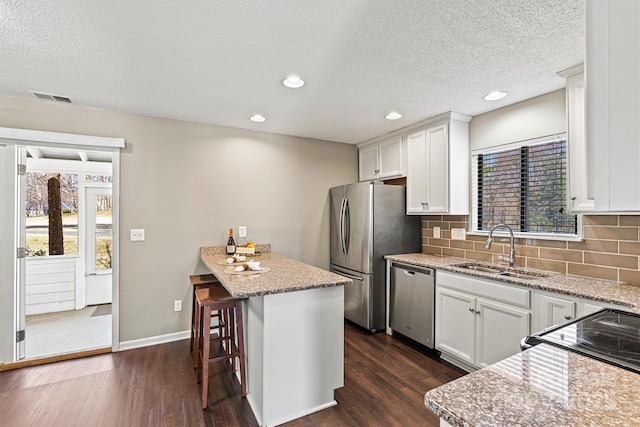 kitchen with a sink, white cabinets, dark wood finished floors, and stainless steel appliances