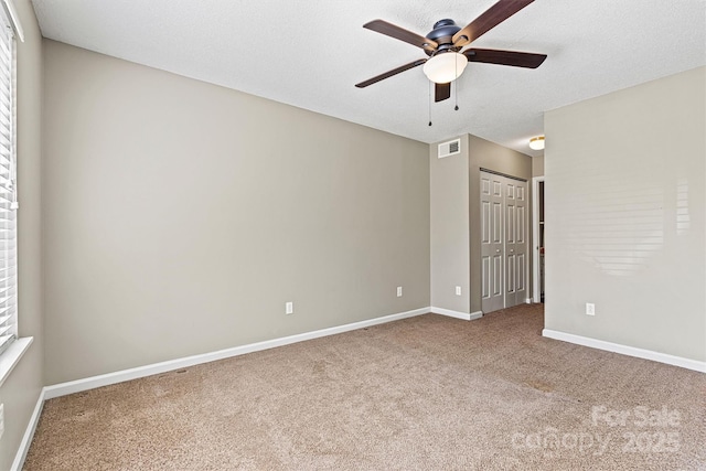 empty room featuring baseboards, visible vents, ceiling fan, a textured ceiling, and carpet flooring