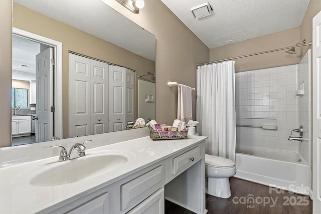 bathroom featuring vanity, wood finished floors, shower / bath combo, a textured ceiling, and toilet