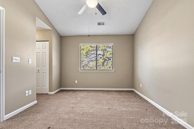 carpeted spare room with ceiling fan, baseboards, visible vents, and a textured ceiling