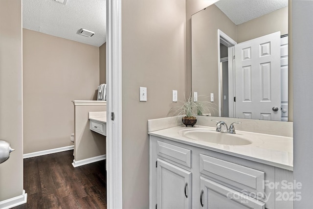 bathroom with a textured ceiling, toilet, and vanity