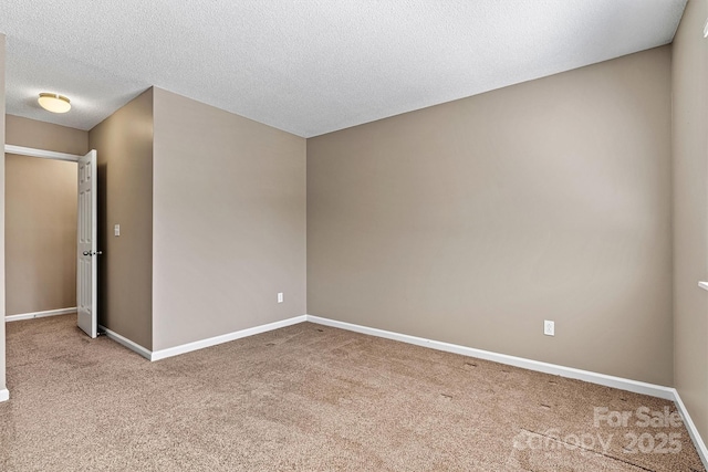 spare room featuring carpet flooring, a textured ceiling, and baseboards