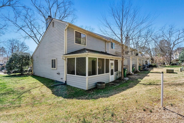 back of property with a yard, a sunroom, and a chimney