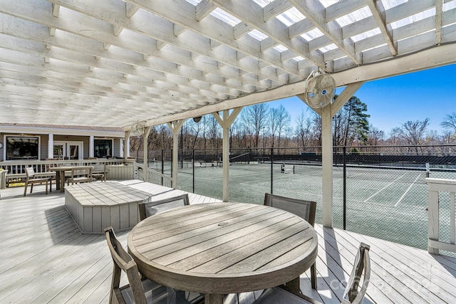 wooden deck featuring outdoor dining space, a pergola, a tennis court, and fence